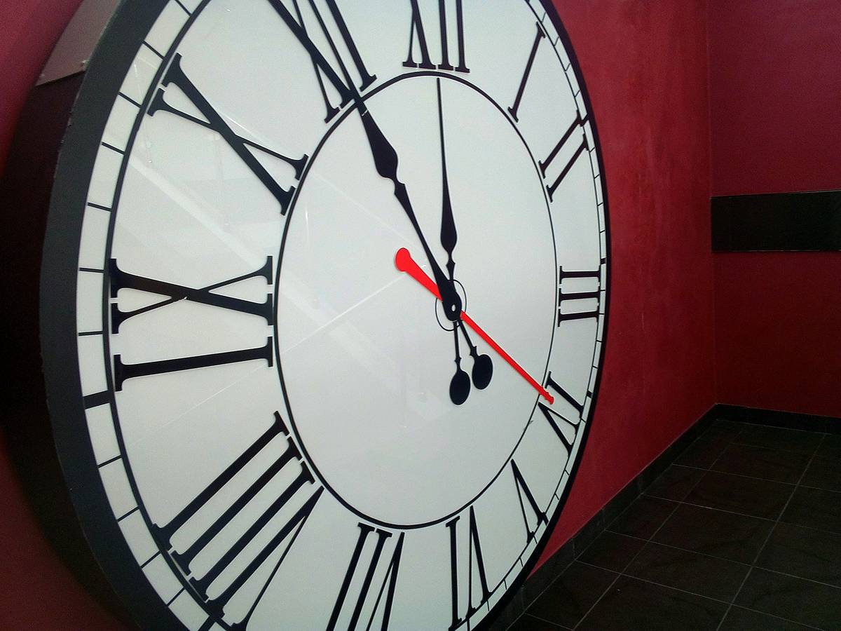 wall clock diy large mounted on a beige living room wall with visible Roman numerals and minimalist black hands